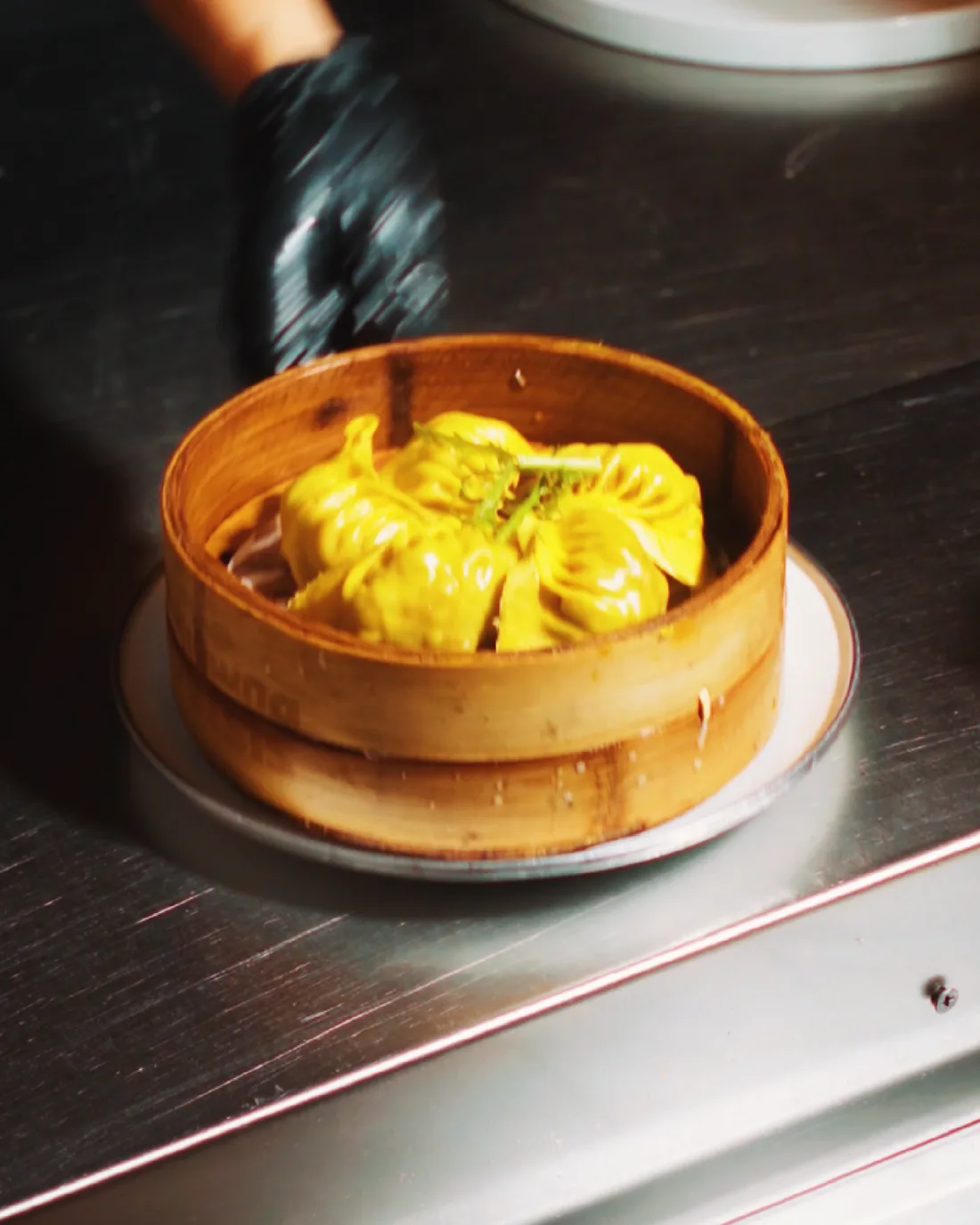 A bamboo steamer of golden dumplings under warm light