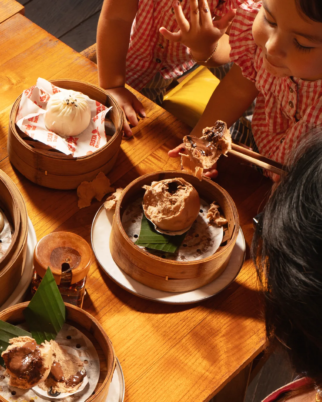 Guests sharing bao and dumplings around a wooden table