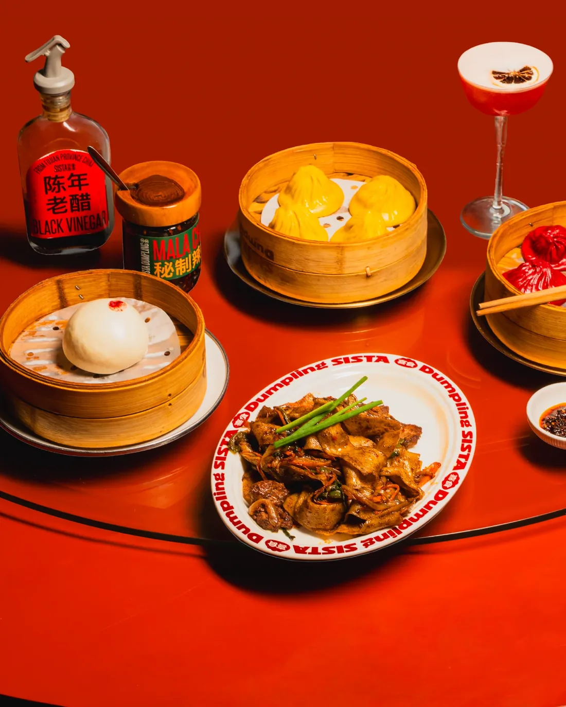Cocktails and steamer baskets of dumplings on the red Sista table